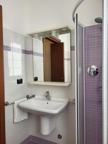 La salle de bains est pourvue d'un lavabo et d'un miroir. dans l'établissement Residence Belvedere Apartment Bolvedro, à Tremezzo
