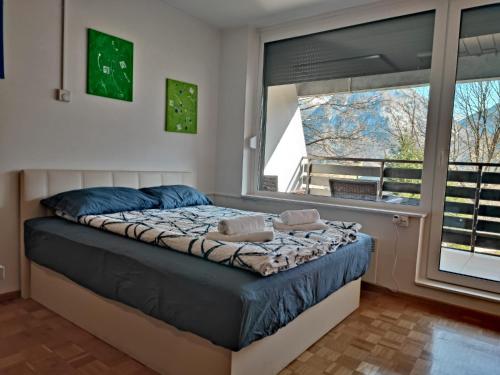 een slaapkamer met een bed met blauwe lakens en een raam bij Studio Kaninska vas in Bovec