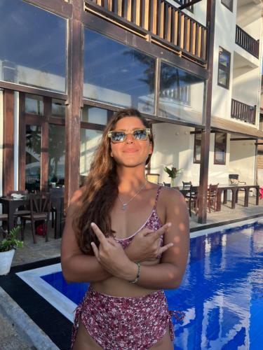 a woman in a bikini standing next to a swimming pool at Surf Station in Ahangama