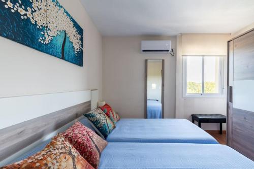 Miraflores Luxury Suites في إشبيلية: غرفة نوم بسرير وملاءات زرقاء ولوحة على الحائط