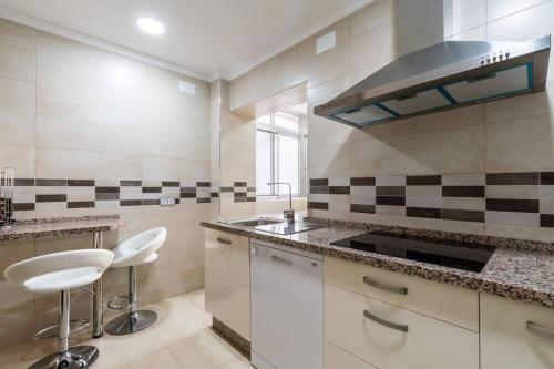 a kitchen with a sink and two stools in it at Miraflores Luxury Suites in Seville