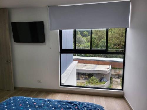 a bedroom with a large window with a table and a tv at Entire Apartment in El Retiro in El Retiro