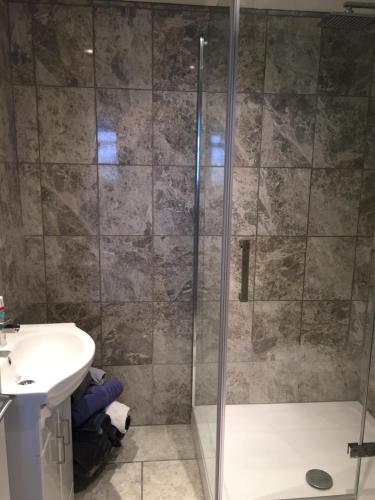 a shower with a glass door next to a sink at The Grooms Quarters in Loughor