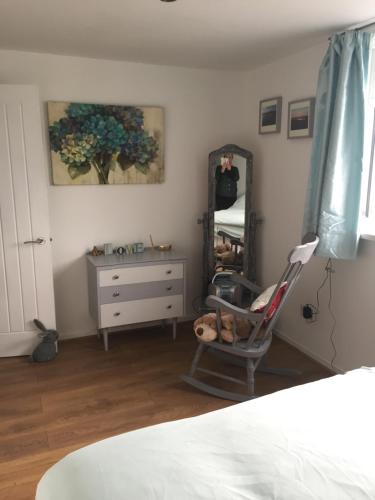 a bedroom with a dresser and a mirror and a chair at The Grooms Quarters in Loughor