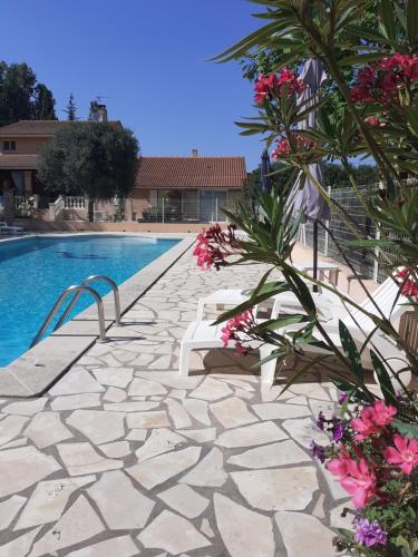 a swimming pool with a stone walkway and flowers at B&B gite d'Ayran in Saint-Quentin-la-Poterie