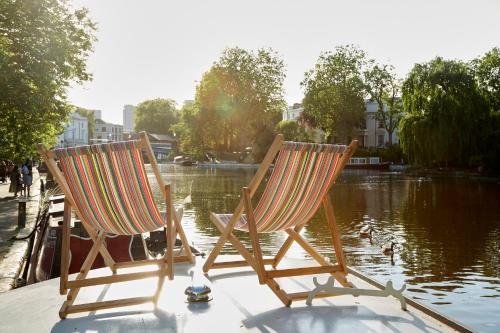 倫敦的住宿－Boutique Barges，两把椅子坐在池塘前的码头上