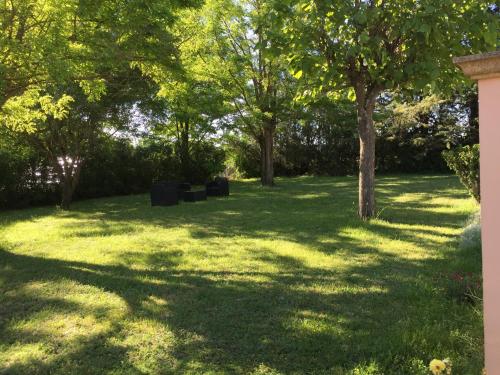 a grassy yard with trees in the shade at B&B gite d'Ayran in Saint-Quentin-la-Poterie