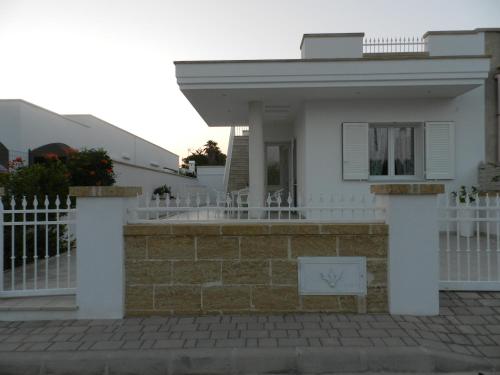 a white house with a fence in front of it at A Pochi Metri Dal Mare in Marina di Mancaversa