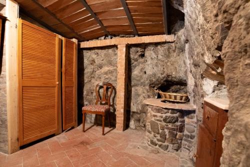 a stone room with a chair and a stone fireplace at La Casetta Nel Borgo in Castelnuovo di Val di Cecina