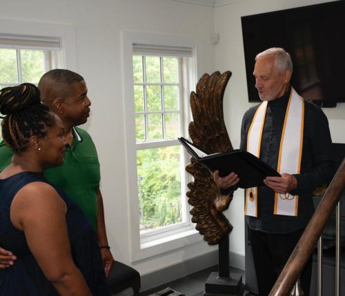 a group of people standing around a man in a room at Old Ivy Walk in Niagara on the Lake