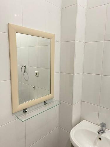 a white bathroom with a mirror and a sink at Mondial apartments in Shymkent