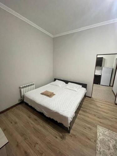 ein weißes Zimmer mit einem Bett und einem Holzboden in der Unterkunft Mondial apartments in Schymkent