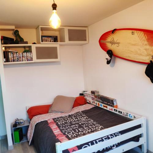 - une chambre avec un lit et une planche de surf sur le mur dans l'établissement GRANDE CHAMBRE LUMINEUSE, au Mans