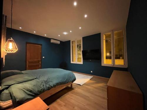 - une chambre avec des murs bleus, un lit et une table dans l'établissement Appartement Haussmannien a 200m des Halles., à Narbonne