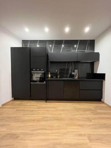 une cuisine avec des armoires noires et un plancher en bois dans l'établissement Appartement Haussmannien a 200m des Halles., à Narbonne