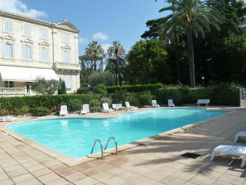 une grande piscine avec des chaises et un bâtiment dans l'établissement VILLAS DES LYS, à Cannes