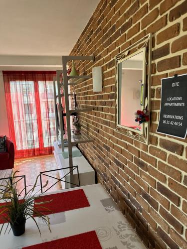 a brick wall with a mirror in a room at Gite Clemenceau in Rouen