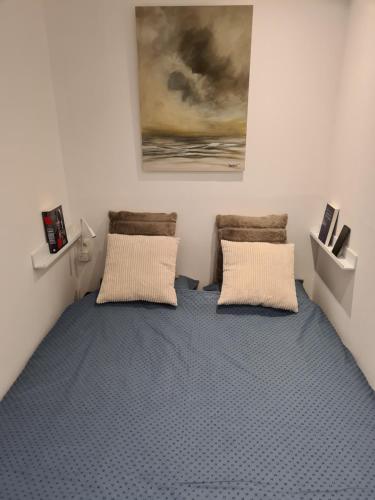a room with a bed with two pillows and a painting at Ensor 1 - centrum Oostende in Ostend