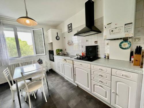 une cuisine avec des placards blancs, une table et une salle à manger dans l'établissement Belle maison 140 m2 à 15 mn de la mer Montpellier, à Teyran