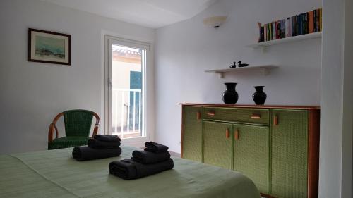 a bedroom with a green dresser and two black towels on a bed at Casa Mirto in Alghero