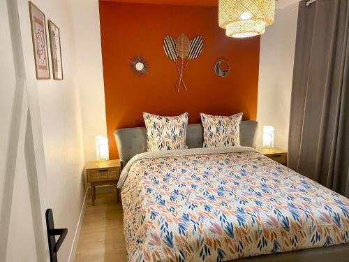 a bedroom with a bed with an orange wall at L'alcôve - Parking, Calme, Terrasse in Castres