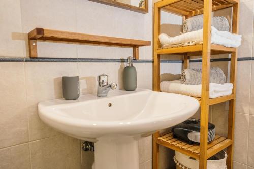 La salle de bains est pourvue d'un lavabo blanc et d'étagères en bois. dans l'établissement APARTAMENTO SANTA CLARA, à Tolède