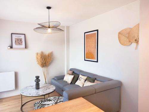 a living room with a blue couch and a table at L'alcôve - Parking, Calme, Terrasse in Castres