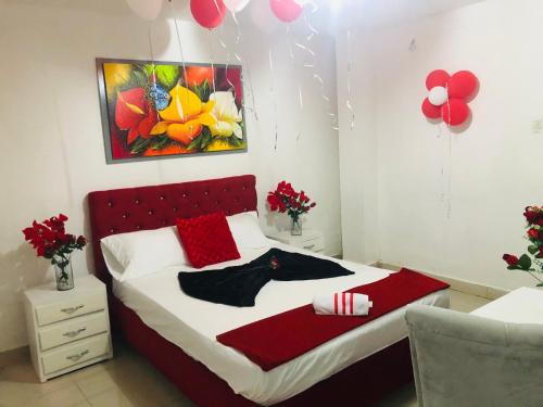 a bedroom with a bed with red pillows and a painting at Hostal Sabanero in Barranquilla