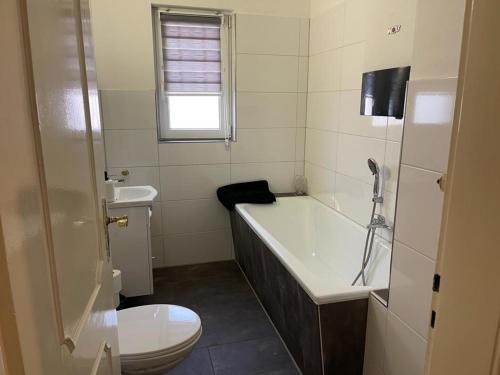 a bathroom with a tub and a toilet and a sink at POLAT Apartments 2 in Essen
