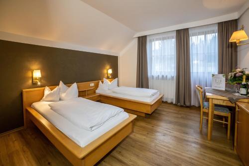 a hotel room with two beds and a table at Lindenhof Hetzenbach in Zell