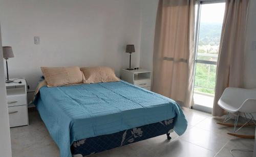 1 dormitorio con 1 cama con edredón azul y ventana en CIELO de Jujuy ll en San Salvador de Jujuy