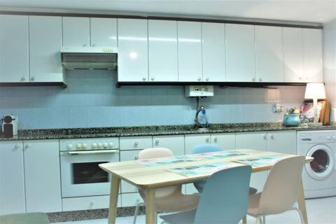 a kitchen with white cabinets and a table and chairs at Acogedor espacio en pleno casco antiguo in Pontevedra