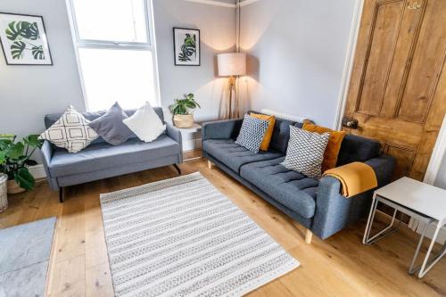 a living room with two blue couches and a rug at Spacious 3 Bedroom House York in York