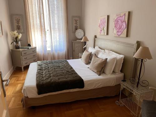 um quarto com uma cama grande com lençóis brancos e almofadas em Magnifique 2 pièces de 65m2 -quartier des Musiciens em Nice