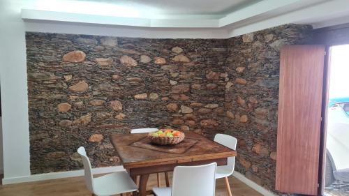 a stone wall in a dining room with a table and chairs at Casa do Adro da Igreja Velha in Janeiro de Cima