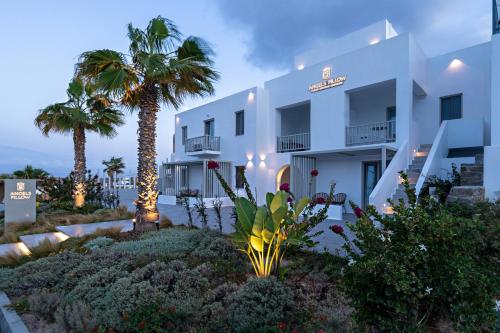 a white building with palm trees in front of it at Angels Pillow Luxury Boutique Residence - Adults Only in Naousa