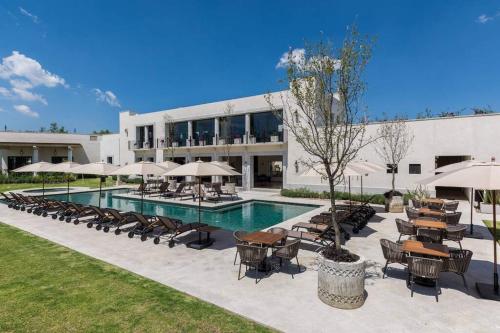 a pool with chairs and umbrellas in front of a building at Depa planta baja en San Miguel de Allende in San Miguel de Allende