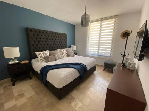 - une chambre avec un grand lit et un mur bleu dans l'établissement Hermoso depa en San Miguel de Allende 2BD-7PAX, à San Miguel de Allende