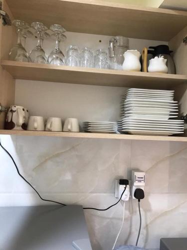 a shelf with plates and cups and dishes on it at Lux Suites Dennis Pritt studio Apartments Kilimani in Nairobi