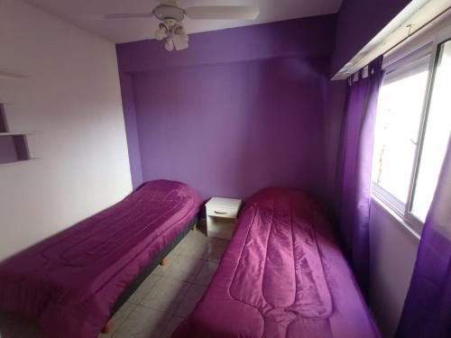 2 camas en una habitación con paredes de color púrpura y ventana en Depto Caba Floresta en Buenos Aires