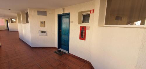 a hallway with a blue door and a tile floor at Monte Gordo T1 Parque dos Reis in Monte Gordo