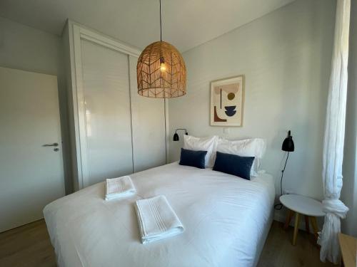 um quarto com uma grande cama branca e um lustre em The Swallows Nest em Lisboa