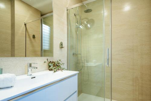 uma casa de banho com uma cabina de duche em vidro e um lavatório. em Apartmentos Marqués de Nervion em Sevilha