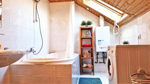 a bathroom with a tub and a sink and a washing machine at Garden Apartment Szolad - Balaton in Szólád