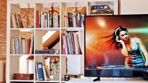 a tv in a book shelf with a woman talking on a phone at Garden Apartment Szolad - Balaton in Szólád