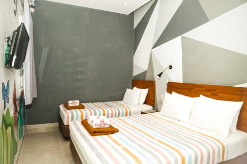 a bedroom with two beds and a tv at Istanaku Guesthouse 2 in Manado