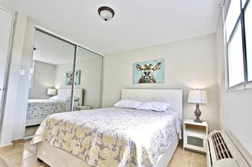 a white bedroom with a bed and a mirror at Ocean & Marina Views 3 Bedroom 2 Bathroom Luxury Condo in Fajardo