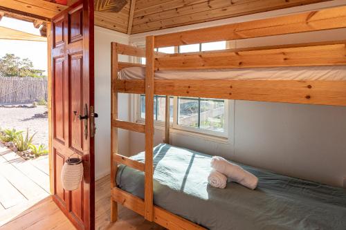 コティージョにあるAlaia Tiny House between volcanoes and beach breaksのベッドルーム1室(二段ベッド2台、窓付)が備わります。