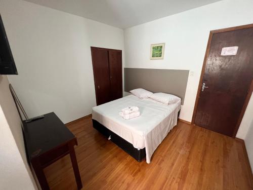 a small bedroom with a bed and a wooden floor at Thermas da Mantiqueira Hotel in Poços de Caldas
