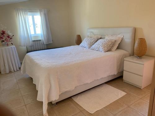 a bedroom with a white bed with pillows and a window at Tavira Unterkunft Entspannung pur!!! in Luz de Tavira